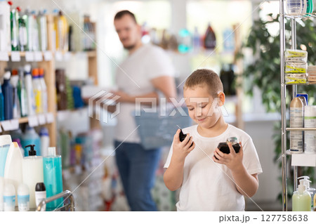 Boy chooses perfume in household chemicals store 127758638