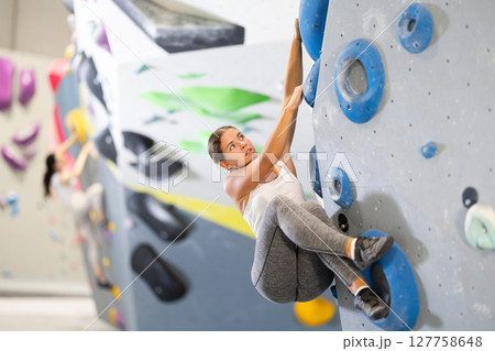 Young woman practicing rock climbing on climbing wall Young woman practicing rock climbing on climbing wall 127758648