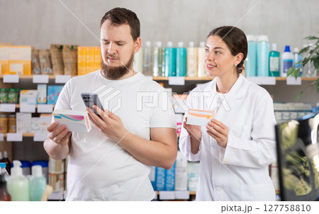 Man scans QR code on box pills label. Female pharmacist offers to choose right shampoo 127758810