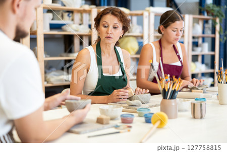 Three pottery workshop workers sculpt from raw clay Three pottery workshop workers sculpt from raw clay 127758815