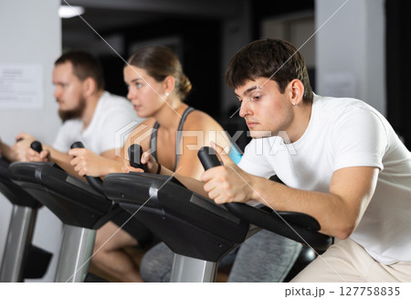 Guy is exercising on an exercise bike 127758835