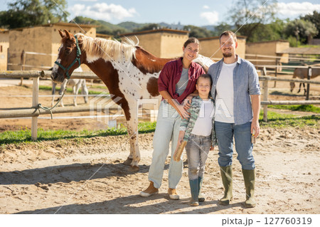 Father, mother and son riding horse together at small horse farm 127760319