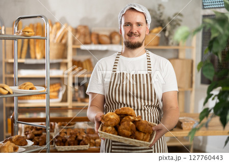 Young male seller with croissants in basket 127760443