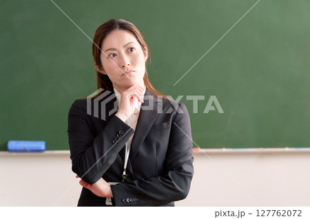 黒板の前で考え事をする女性教師 127762072