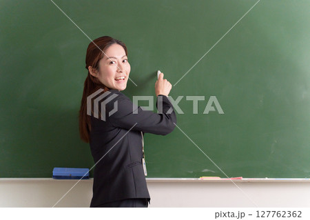 黒板の前で振り返る女性教師 127762362