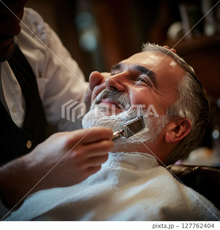 the barber is using a professional razor carefully gliding it along the client's jawline with precision and expertise 127762404
