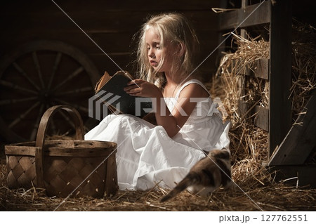 Girl with a kitten on hay 127762551