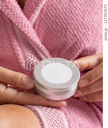 Woman in pink bathrobe holding body butter jar with a label in hands, Closeup, cosmetic mockup Woman in pink bathrobe holding body butter jar with a label in hands, Closeup, cosmetic mockup 127763073