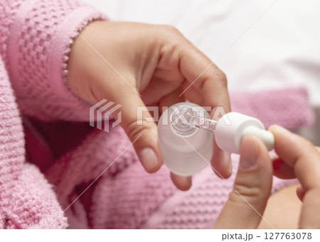 Closeup of young woman in pink bathrobe opening dropper bottle top view, cosmetic mockup Closeup of young woman in pink bathrobe opening dropper bottle top view, cosmetic mockup 127763078