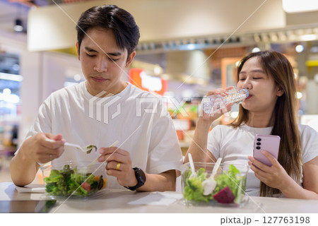 Young couple eating salad together Young couple eating salad together 127763198
