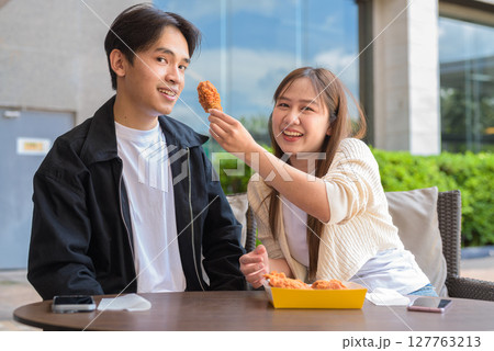 Young Asian couple eating fried chicken Young Asian couple eating fried chicken 127763213