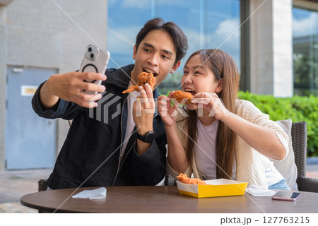 Young Asian couple eating fried chicken Young Asian couple eating fried chicken 127763215