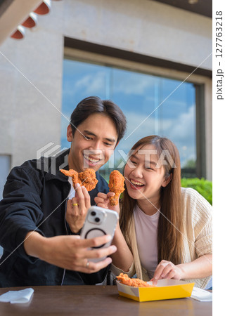 Young Asian couple eating fried chicken Young Asian couple eating fried chicken 127763218