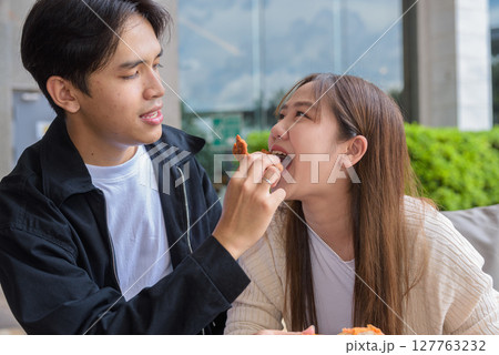 Young Asian couple eating fried chicken Young Asian couple eating fried chicken 127763232