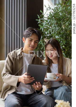 Couple using tablet computer in cafe while having coffee 127763254