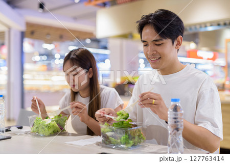 Young couple eating healthy salad indoors 127763414
