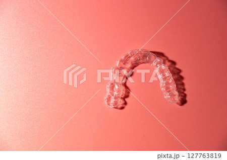 Close up of invisible aligners on pink background with copy space. Plastic braces dental retainers for teeth straightening Close up of invisible aligners on pink background with copy space. Plastic braces dental retainers for teeth straightening 127763819