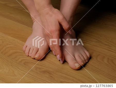 Close-up of a woman s foot with hallux valgus bunion and signs of toenail fungus. Her hand gently touches the deformed big toe, illustrating common foot problems and the need for medical care. 127763865
