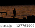 夕方に釣りをする人のシルエット 127763909