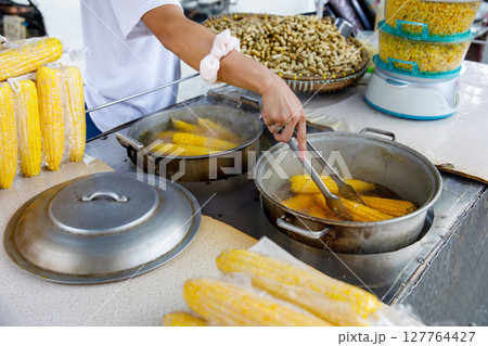 Filipino vendor boiling corn on street food stall with peanuts and steamed kernels in background 127764427