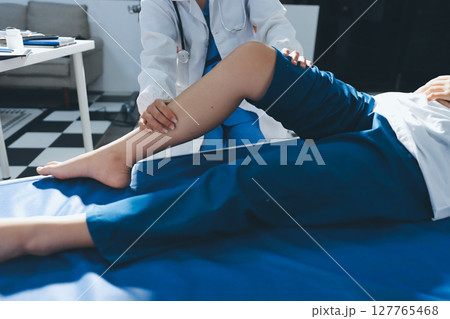 Female doctor hands doing physical therapy By extending the leg and knee of a male patient Female doctor hands doing physical therapy By extending the leg and knee of a male patient 127765468