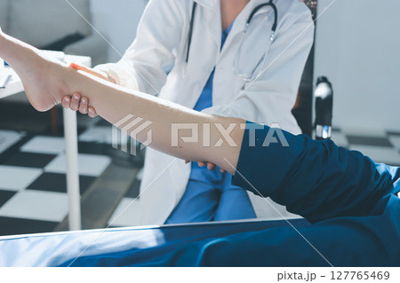 Female doctor hands doing physical therapy By extending the leg and knee of a male patient Female doctor hands doing physical therapy By extending the leg and knee of a male patient 127765469