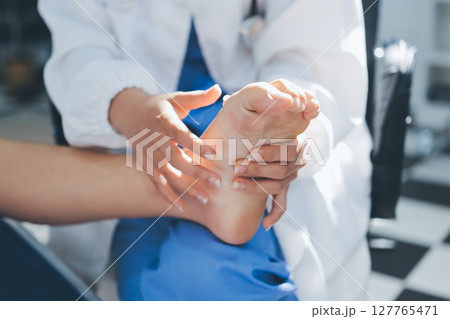Female doctor hands doing physical therapy By extending the leg and knee of a male patient Female doctor hands doing physical therapy By extending the leg and knee of a male patient 127765471