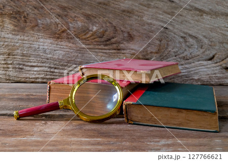 Vintage magnifying glass with old books. Concept for learn history. Vintage magnifying glass with old books. Concept for learn history. 127766621