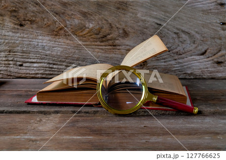 Vintage magnifying glass with old books. Concept for learn history. Vintage magnifying glass with old books. Concept for learn history. 127766625