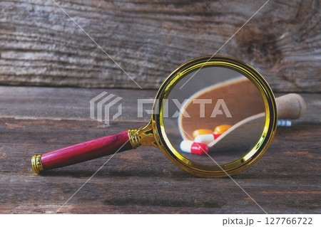 Magnifying glass with pharmaceutical medicine pills, 127766722