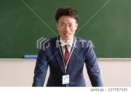 黒板の前に立つ笑顔の男性教師 127767191
