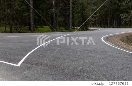 A paved road curves in a forested area, marked with directional arrows A paved road curves in a forested area, marked with directional arrows 127767631