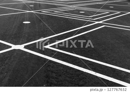 A detailed view of intersecting white lines on an asphalt surface, A detailed view of intersecting white lines on an asphalt surface, 127767632