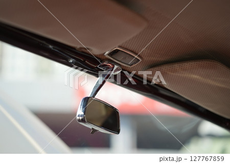 The rearview mirror of a classic car has a shiny chrome finish with a simple design, serving as a practical feature that adds elegance to the interior. The rearview mirror of a classic car has a shiny chrome finish with a simple design, serving as a practical feature that adds elegance to the interior. 127767859