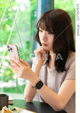 スマートフォンの画面を見て考える女性 127767973