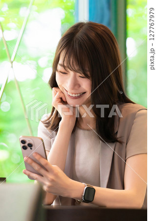カフェでスマートフォンを使う笑顔の女性 127767979