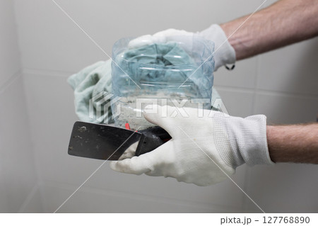 Trowel and cement glue for bathroom renovation work in male hands close up Trowel and cement glue for bathroom renovation work in male hands close up 127768890