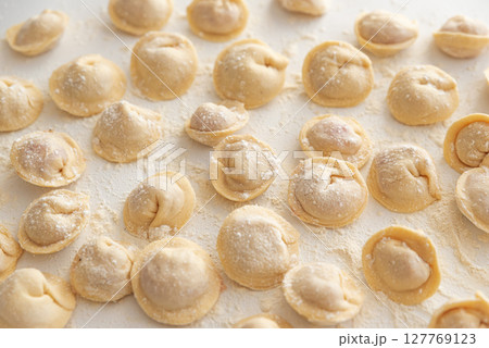 Raw homemade dumplings dusted with flour. Raw homemade dumplings dusted with flour. 127769123