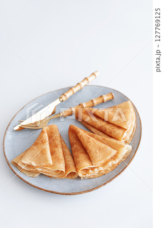 Golden crepes on white wooden table. Pancake day, Maslenitsa. Top view Golden crepes on white wooden table. Pancake day, Maslenitsa. Top view 127769125