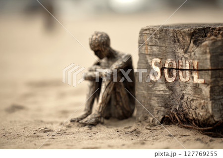 Contemplative Wooden Figure Beside Weathered Post with Soul Inscription. 127769255
