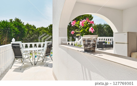 Bright Mediterranean-style terrace framed by white arches Bright Mediterranean-style terrace framed by white arches 127769301