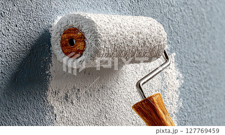 Paint roller applying fresh white paint on a blue wall for home renovation project 127769459