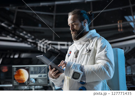 Cosmonaut in orbital station ensuring operational readiness before mission launch to Mars. Man working on spaceship doing Martian surface research to advance scientific knowledge 127771435