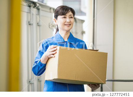 物流倉庫で段ボールを運ぶミドル世代の女性 物流倉庫で段ボールを運ぶミドル世代の女性 127772451