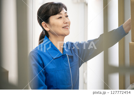 作業服を着て物流倉庫で働くミドル世代の女性 127772454