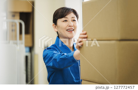 作業服を着て物流倉庫で働く50代の女性 127772457