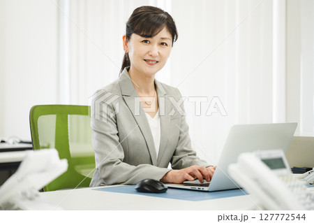 ビジネスオフィスでデスクワークをする50代のキャリアウーマン 127772544