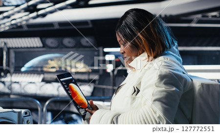 Astronaut using tablet to check analytics after completing red planet surface mission on unfamiliar planet. Cosmonaut leaving Mars, inputting navigation coordinates on device to return home Astronaut using tablet to check analytics after completing red planet surface mission on unfamiliar planet. Cosmonaut leaving Mars, inputting navigation coordinates on device to return home 127772551