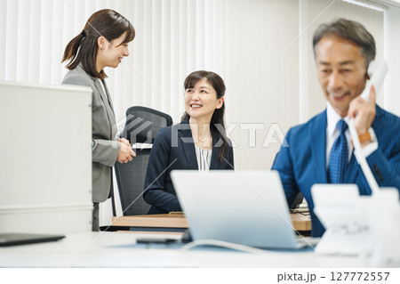 オフィスで部下と話す管理職の女性 127772557