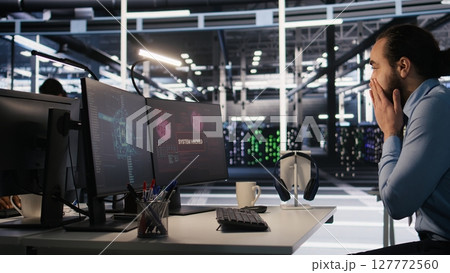 Employee requesting help from manager to fix hacked equipment systems. Stressed data center admin reacting to spyware popup on computer screen, launching emergency response protocol, camera A 127772560